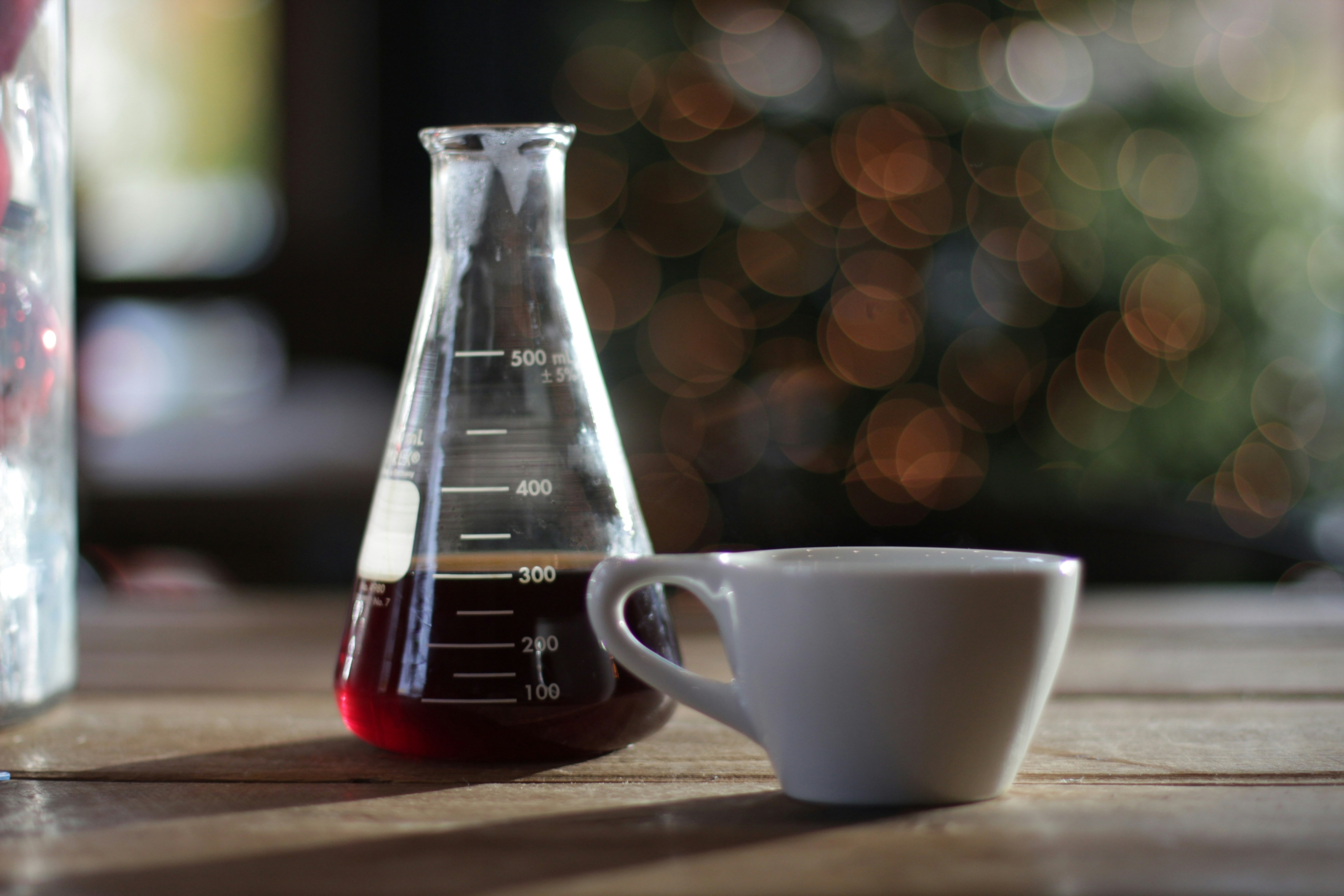 A white mug next to a chemistry beaker of coffee.